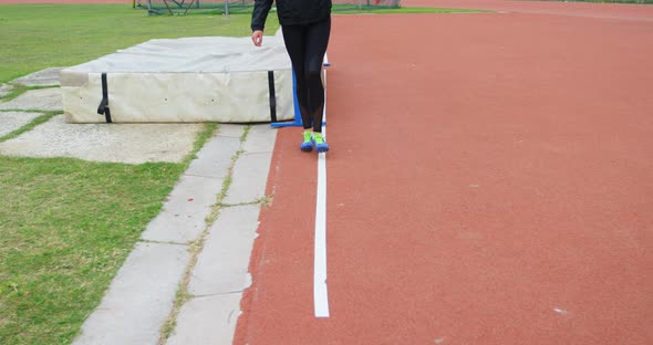 Low section of female athlete measuring high jump field with footstep 4k