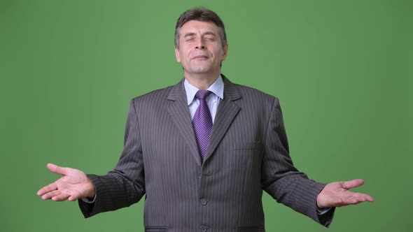 Mature Handsome Businessman Against Green Background