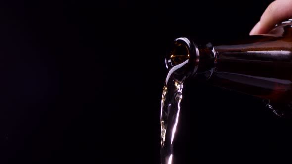 Beer Pouring From Bottle on Black Background