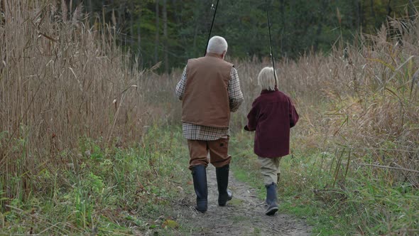 Grandfather and Grandson Carrying Fishing Rods While Walking