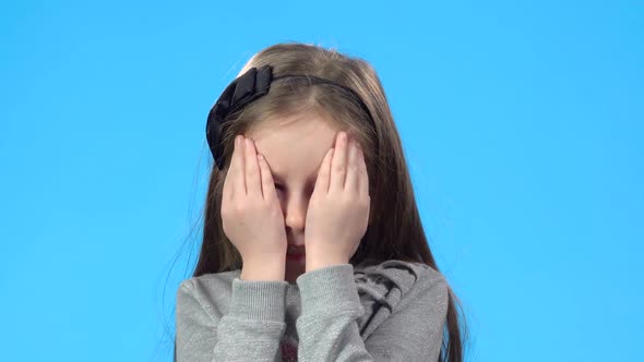 Blonde Girl Is Smiling and Closing Her Face with Palms.