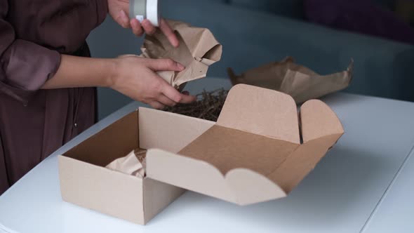 Woman is Packing Jars of Cosmetics in a Box to Send a Parcel Through a Delivery Service