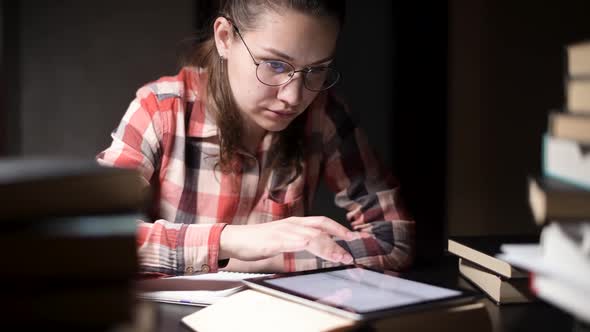 girl searches for information in book, but does not find it, so she takes tablet