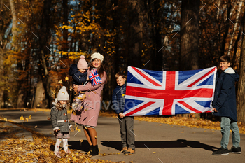 itish flags in autumn park.  Britishness celebrating UK. Mother with four kids.