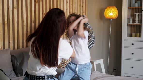 Amazed Preschooler Girl Hits Brunette Mother with Pillow