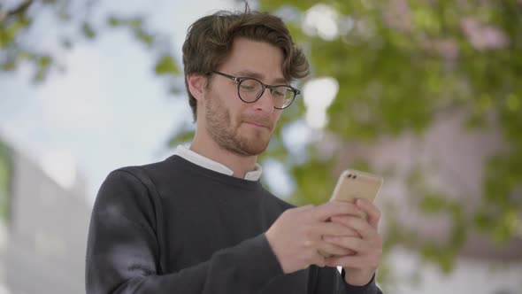 Smiling Man in Eyeglasses Using Smartphone