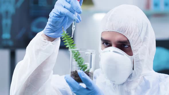 Dolly Shot of Scientist in White Coverall Making Experiments on Plants alt