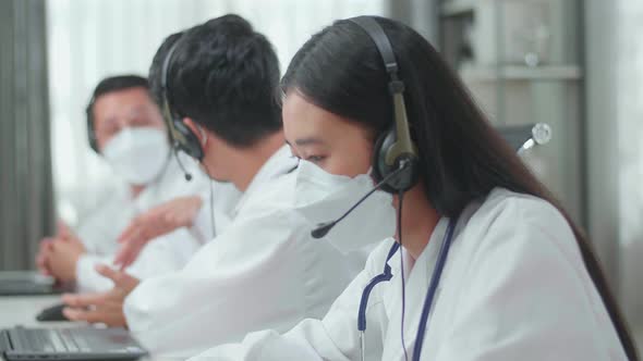 Woman Doctor In  Masks Working As Call Centre Agent Speaking To Customers While Colleagues Talking