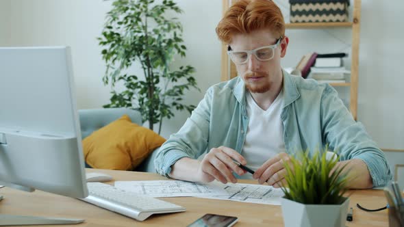 Handsome Gingerhaired Man Architect Working at Home Drawing Plan and Using Computer