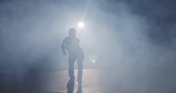 female dancer performing hip hop dance in slow motion with light and smoke background