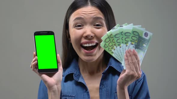 Excited Asian Woman Showing Smartphone and Bunch of Euros, Cash Back Services