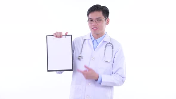 Happy Young Asian Man Doctor Showing Clipboard and Giving Thumbs Up