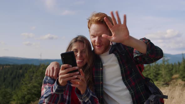 Happy Man and Woman Waving Hands at Smartphone Camera During Video Chat
