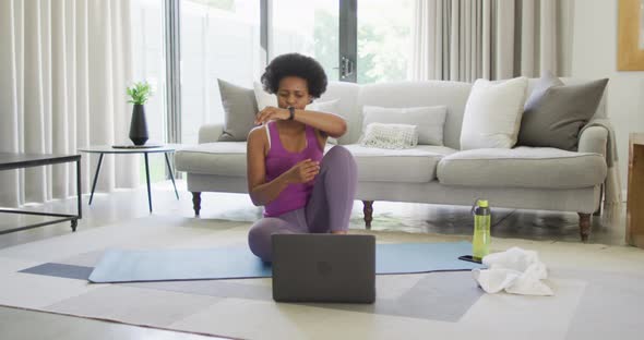 Happy african american wearing sportswear, exercising, using laptop