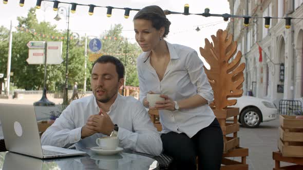 Businessman and Businesswoman on Video Conference with Them Colleague in Cafe