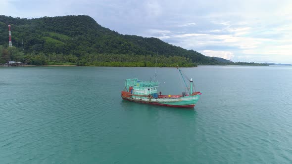 Drone shot of a wooden fishing boat towing a sinking boat behind. 4K