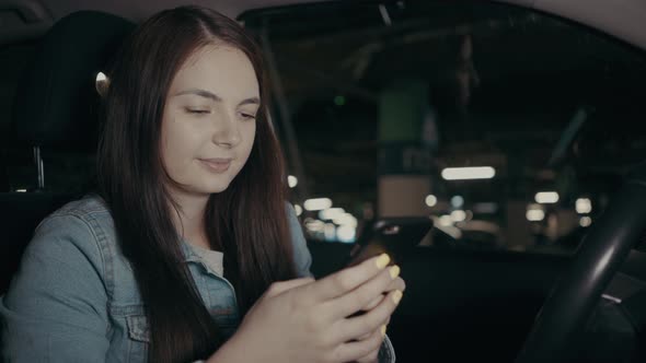 Woman Uses an Application on His Phone While Sitting in the Car in the Parking Lot