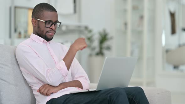 Pensive African Man Thinking and Working on Laptop at Home 