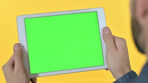 Man Holding Tablet with Chroma Screen, Yellow Background