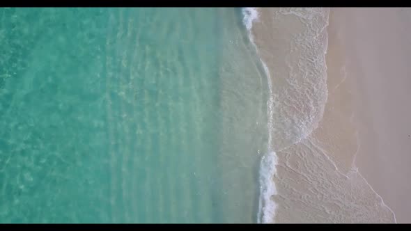 Aerial drone shot travel of perfect seashore beach adventure by blue green sea with white sandy back