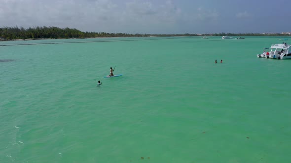 Circling around people swimming and paddle-boarding in incredible turquoise ocean water, Playa Jauni