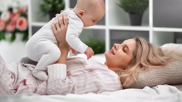 Pleasant Woman Hold Baby in Sliders Enjoying Happy Motherhood