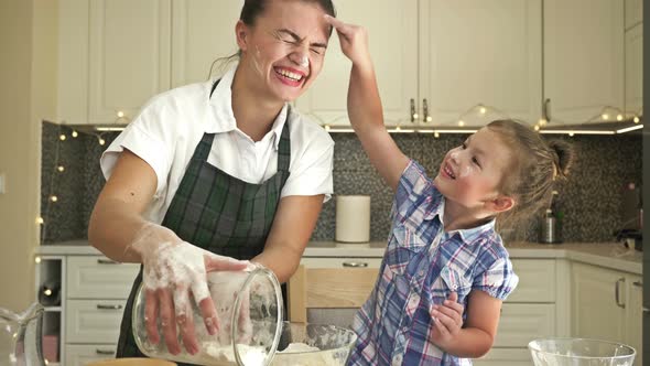 Little Daughter Helps Her Mother To Cook Some Dough