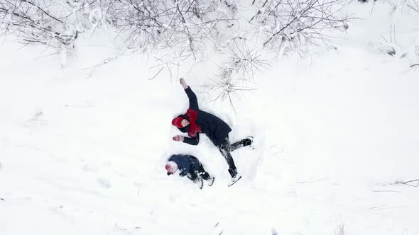 Mom and Son Lie in the Snow and Make an Angel