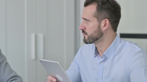 Businessman with Tablet Talking to Colleagues