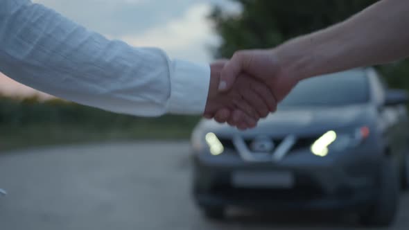 Close Up View of a Two Man Shake Their Hands Grey Car