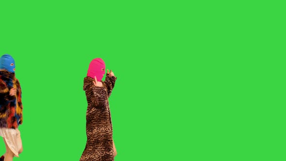 Three Girls in Colored Balaclavas Walk Fast in Defiant Manner on a Green Screen Chroma Key