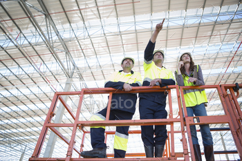 Low angle view of site managers and architect pointing from viewing platform on construction site