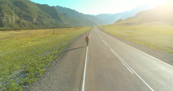 Flight Over Hitchhiker Tourist Walking on Asphalt Road