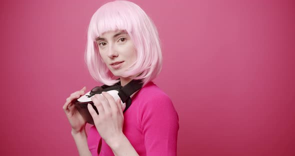 Woman Uses a Virtual Reality Glasses on Isolated Pink Background