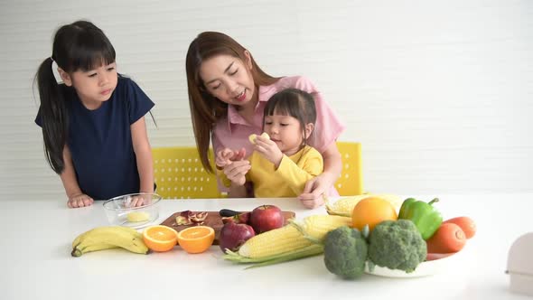 Asian mother, feeding apple fruits for her two daughters