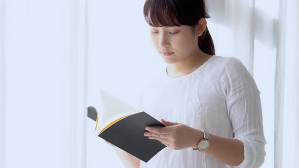 Young asian woman relax and leisure standing learning with reading book for exam.