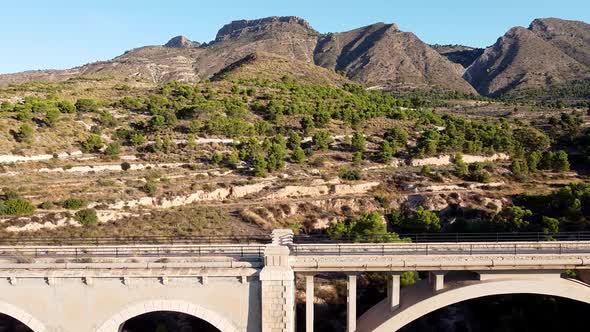 Close up. Flying along a stone bridge with mediterranean mountains in the background..