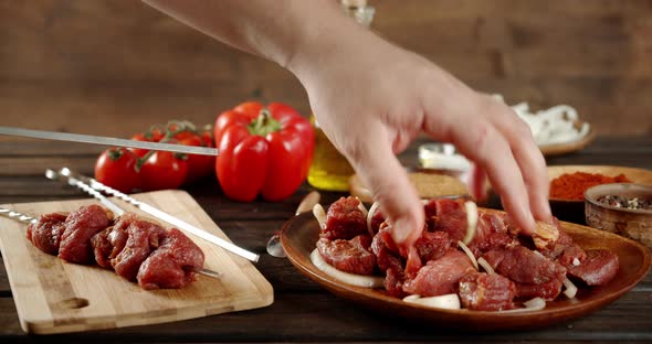 Men's Hands Incandescent Raw Pork Kebab on a Skewer. 