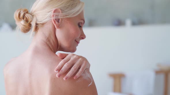 Back View of Mid Age Woman Applying Body Cream