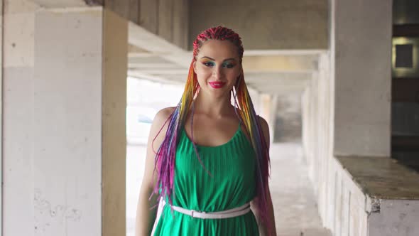 A Girl with a Happy Smile in a Spring Dress with Bright Makeup and Multicolored Braids is Spinning