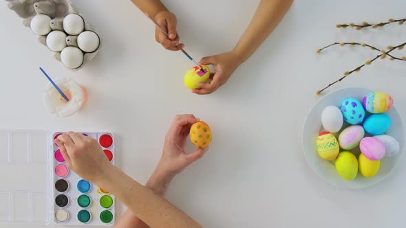 Hands of Child and Parent Coloring Easter Eggs