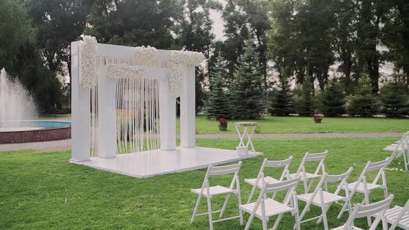 beautiful wedding arch in the park with white chairs