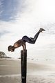 Young man training, doing handstand with raised legs on wooden beach posts - PhotoDune Item for Sale