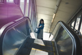 Mid adult woman using escalator, holding smartphone, elevated view - PhotoDune Item for Sale