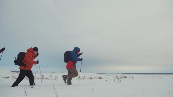 Three Tourist Hikers with Trekking Poles, a Backpack and Snowshoes. Happy Hikers Group Walking