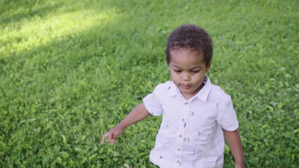 A Little African Boy Happily Runs Along the Green Lawn