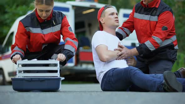 Paramedics Making Injection Male Feeling Chest Pain and Lying on Road, First Aid