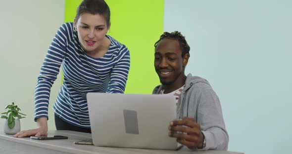 Positive Smiling Man and Woman Near Working Place with Laptop Cooperating in Office