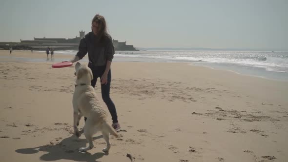 Smiling Young Woman and Dog Playing with Red Flying Disk