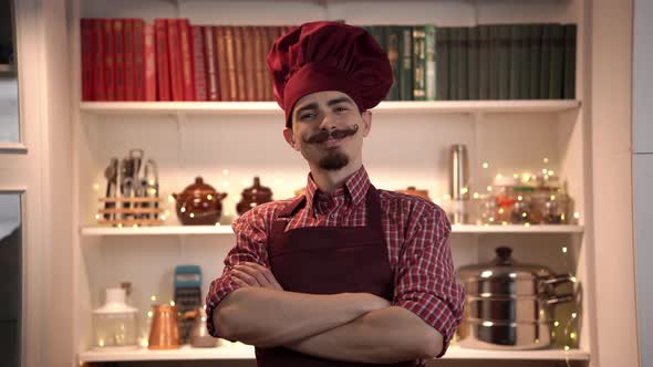 Portrait of Smiling Young Cook Wearing Red Toque with Apron and Standing with Crossed Arms